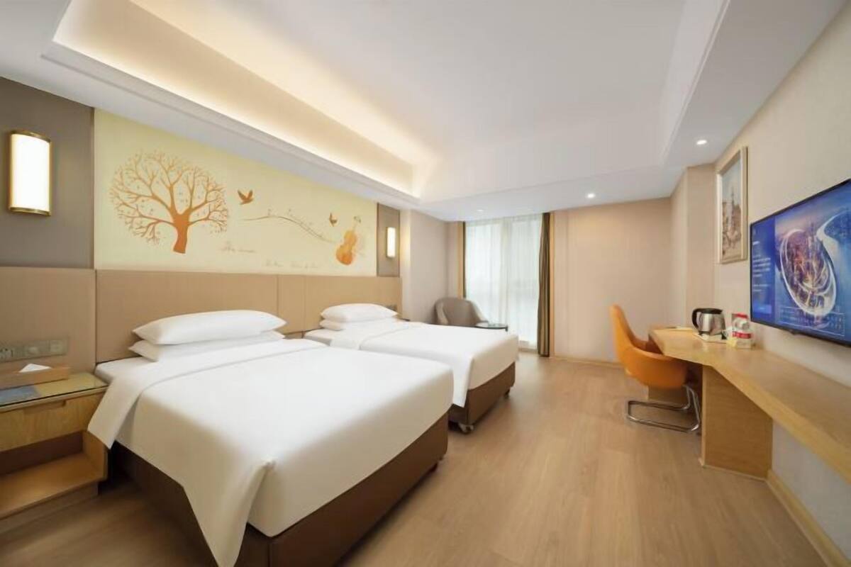 A hotel room with two beds, a desk, a chair, and a large painting on the wall.