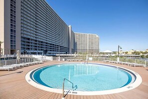 En swimmingpool omgiven av en terrass med utsikt över höga byggnader.
