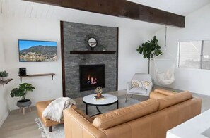 Cozy up by the fireplace in this stylish living room, featuring a comfortable sofa, armchair, and mounted TV.