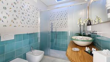 A modern bathroom with a glass shower enclosure, a white bidet, a wooden vanity with a large sink, and a mirror with a vase of flowers.