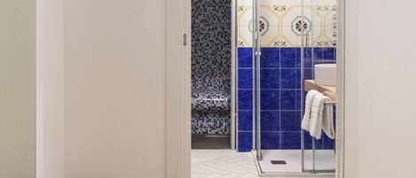 A bathroom with a shower, a tiled wall, and a white floor.