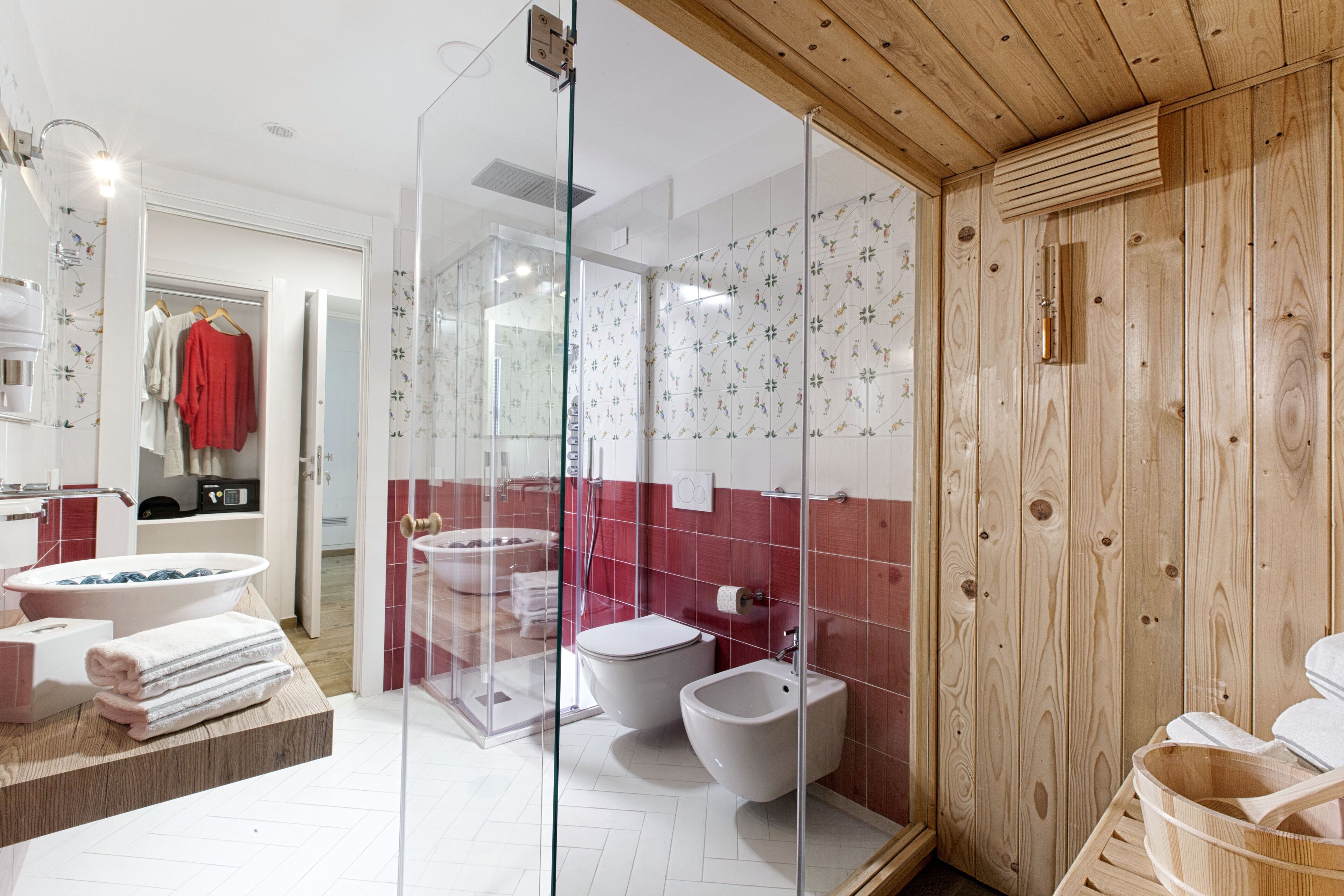 A modern bathroom with a glass shower enclosure, a bidet, and a wooden sauna area.