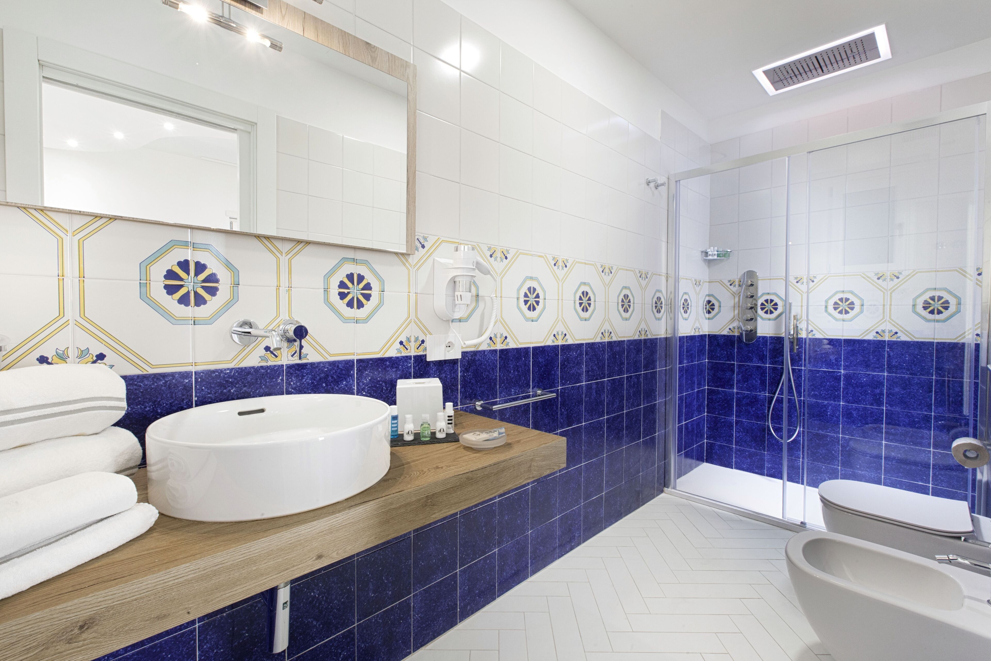 Un bagno moderno con un lavandino capiente, uno specchio, una doccia e un WC.
