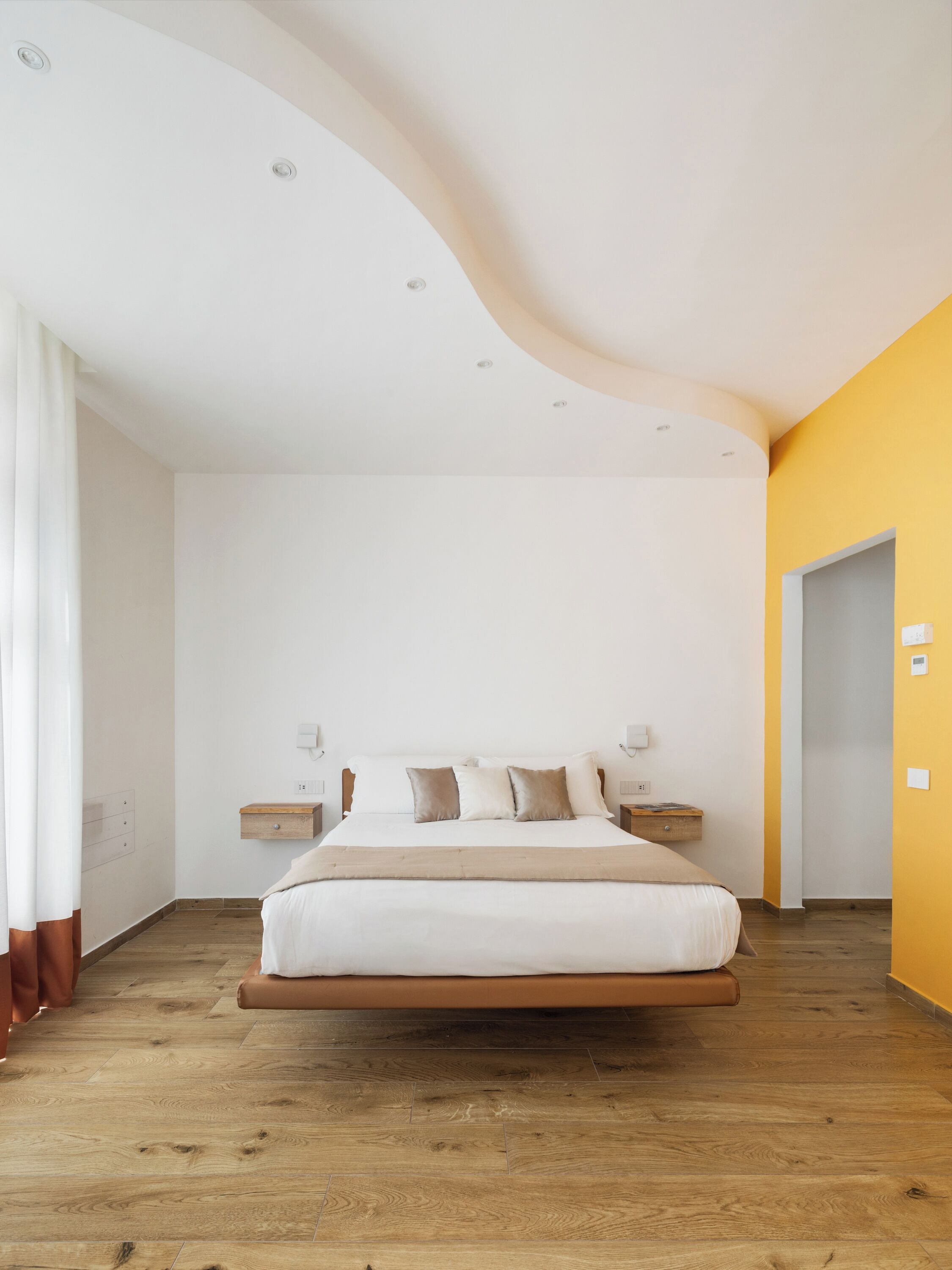 Ein modernes Schlafzimmer mit Holzboden, einem Bett mit weißer Bettwäsche und einer gewölbten Decke.