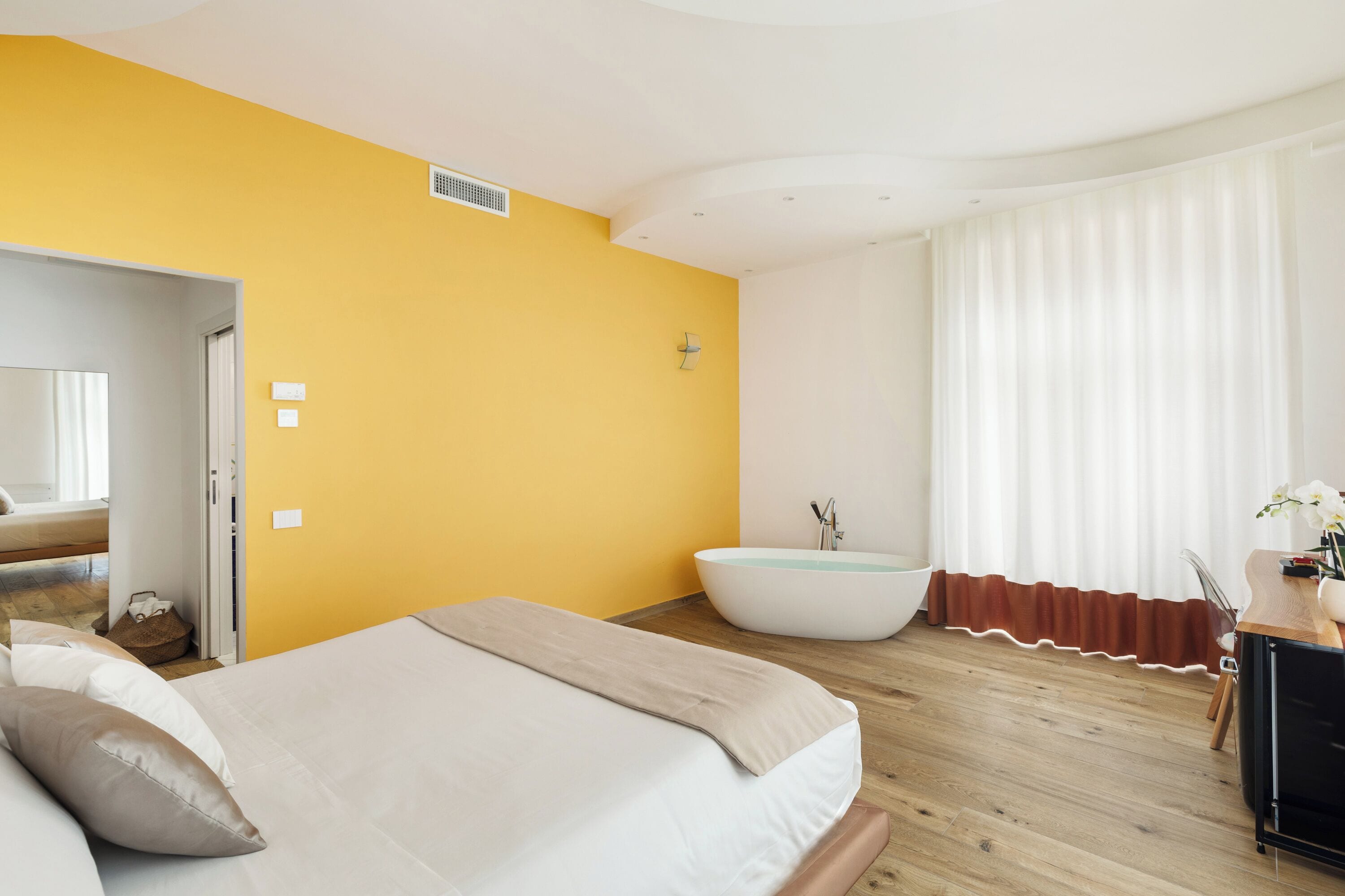 Une chambre à coucher avec un lit, une baignoire et un plancher en bois.