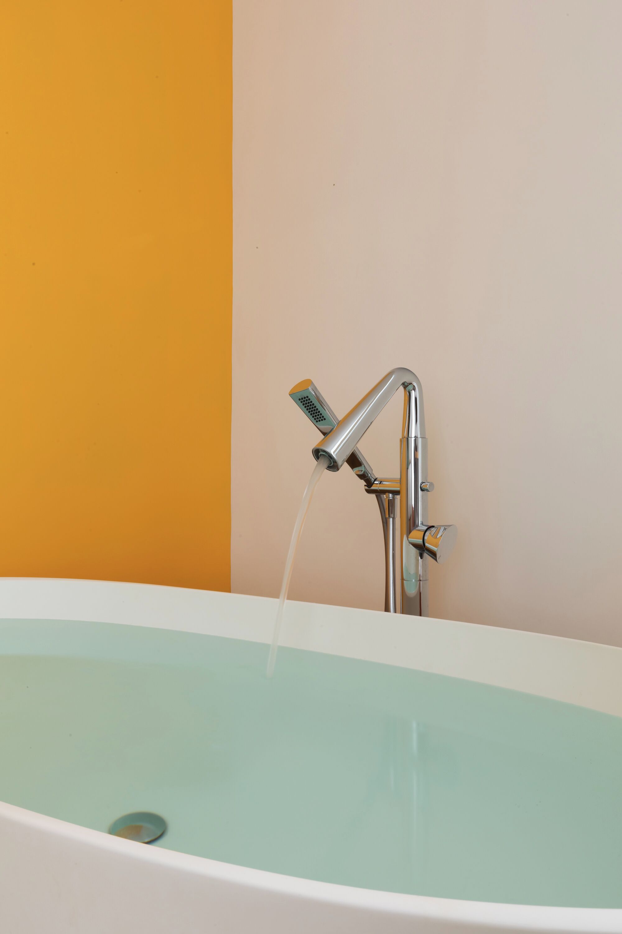 A bathtub with running water, a chrome faucet, and a drain.