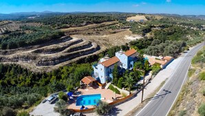 Un'ampia casa con piscina, situata vicino a una strada da cui si gode una vista panoramica del paesaggio circostante.