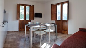 A compact kitchen with a dining area, wooden cabinets, and a flat-screen TV.