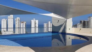 A rooftop pool with a clear view of high-rise buildings and the ocean in the background. - Apartamentos Velas al Mar Rodadero (Santa Marta)