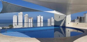 A rooftop pool with a clear view of high-rise buildings and the ocean in the background. - Apartamentos Velas al Mar Rodadero (Santa Marta)