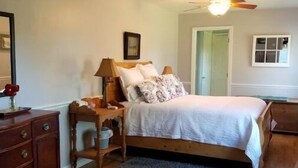 A bedroom with a wooden bed, a nightstand, a dresser, and a ceiling fan. - Drennen Ridge Farm Guest House (Marlinton)