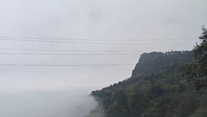 Un paysage montagneux avec une falaise boisée et des lignes électriques.