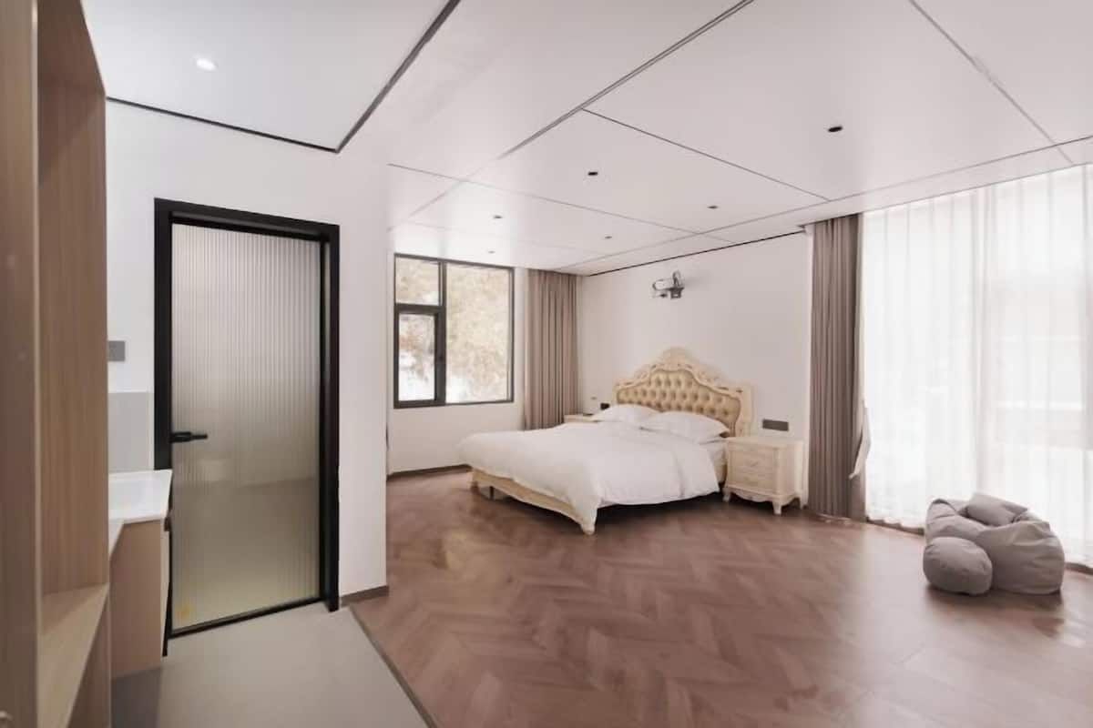 Een moderne slaapkamer met een bed, nachtkastjes, een kledingkast en een relaxfauteuil.