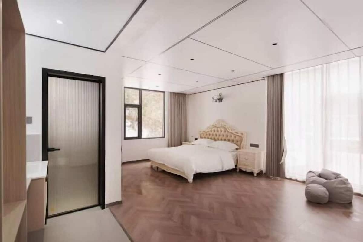 Een moderne slaapkamer met een groot bed, nachtkastje, garderobe en een raam met gordijnen.