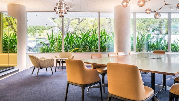 Une salle de conférence moderne, dotée d’une grande table, de chaises confortables et de larges fenêtres donnant sur un paysage verdoyant.