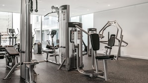 Une salle de sport équipée de divers appareils d’entraînement, notamment un appareil à câbles, une machine à presses pour les jambes et un banc de développé couché.