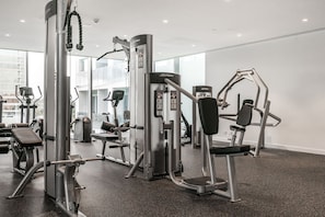 Una palestra con diverse macchine per esercizi, tra cui una macchina a cavi, una pressa per le gambe e una panca per pesi.