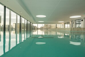 A swimming pool with a tiled floor and large windows on one side. - The Fawkner Stylish Saint Kilda Apartment (Melbourne)