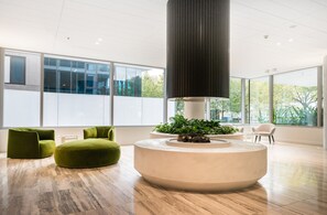 A modern interior with a round seating area, large windows, and a central column. - The Fawkner Stylish Saint Kilda Apartment (Melbourne)