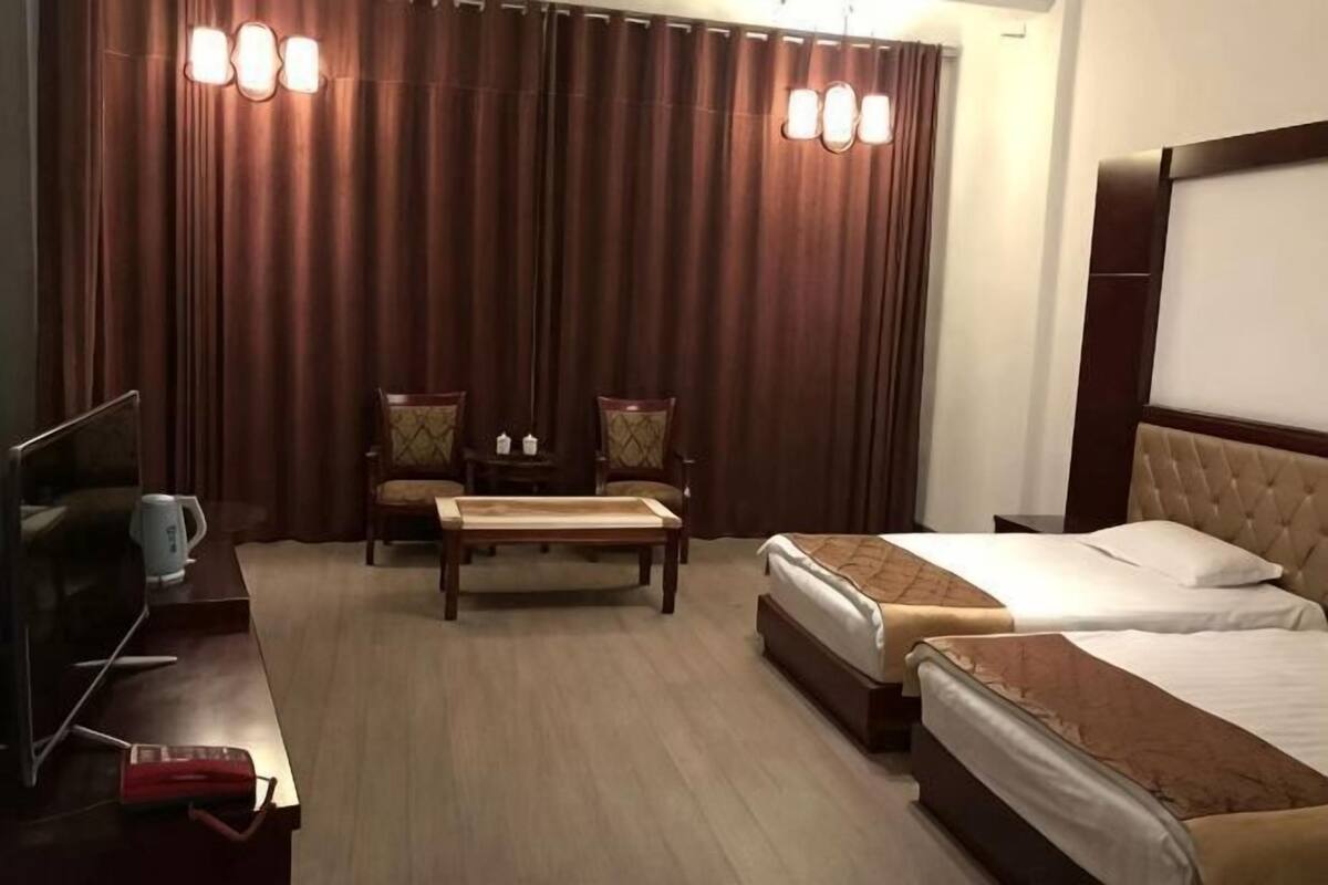 A hotel room with a bed, two chairs, a TV, and a coffee table.