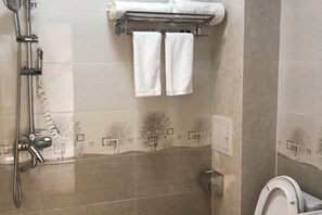 Un baño con ducha, inodoro y toallero.