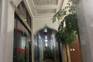 A corridor with glass doors, a ceiling with decorative panels, and a potted plant.