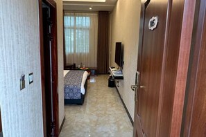 A hotel room with a bed, a desk, a TV, and a wardrobe. - Weishan Gulan Impression Hotel (Weishan)