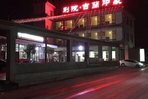 A building with a prominent sign, large windows, and a parked car. - Weishan Gulan Impression Hotel (Weishan)