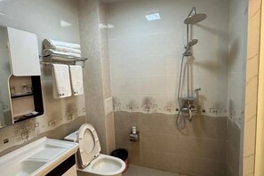 A bathroom with a toilet, a sink, a mirror, a towel rack, and a shower. - Weishan Gulan Impression Hotel (Weishan)