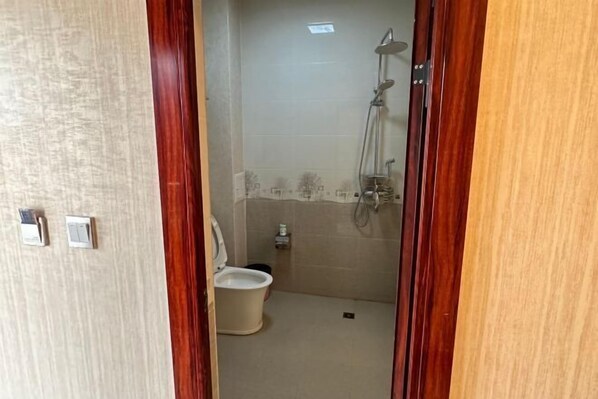 A small bathroom with a toilet, a shower, and a sink. - Weishan Gulan Impression Hotel (Weishan)