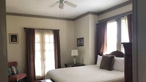 Ein Hotelzimmer mit einem großen Bett, einem Schreibtisch, einem Stuhl und einem Deckenventilator.