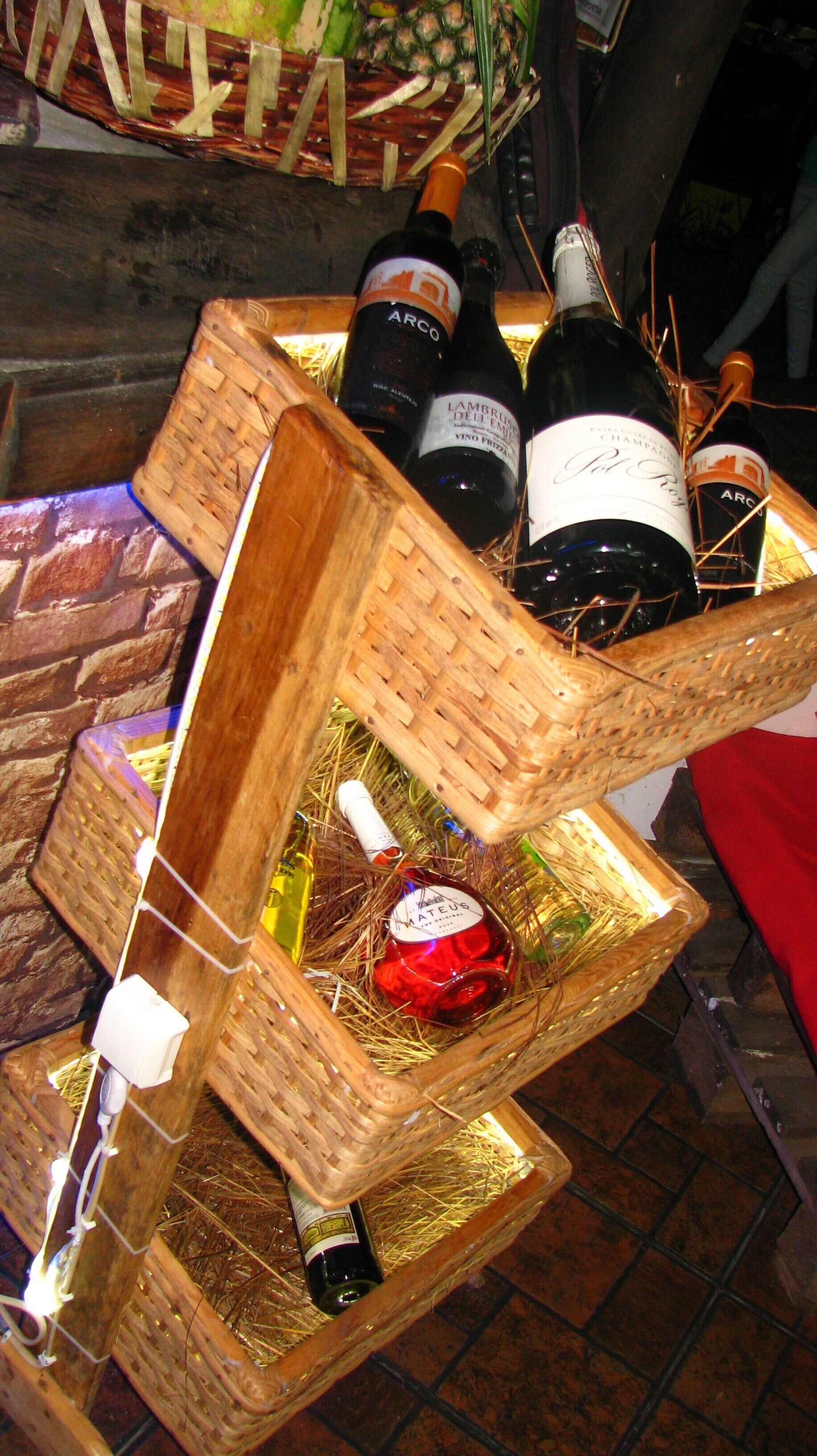 A wicker wine rack with bottles and a pineapple.