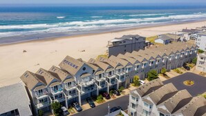 A coastal hotel with multiple-story buildings, a beach view, and a parking area.