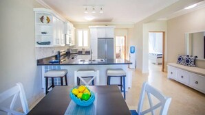 Une cuisine moderne avec des meubles blancs, un plan de travail noir et un coin repas comprenant une table et des chaises.