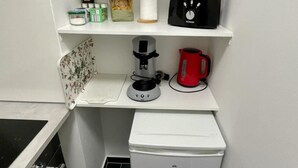 Une cuisine compacte équipée d’un four à micro-ondes, d’une machine à café et d’un petit réfrigérateur.