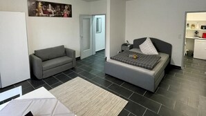 Une chambre moderne et bien éclairée, comprenant un lit, un canapé et un coin repas.