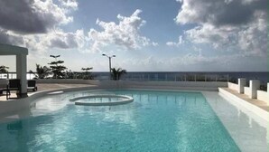 A swimming pool with a view of the ocean and a clear sky. - Estudio frente al mar de Cozumel #5 (San Miguel de Cozumel)