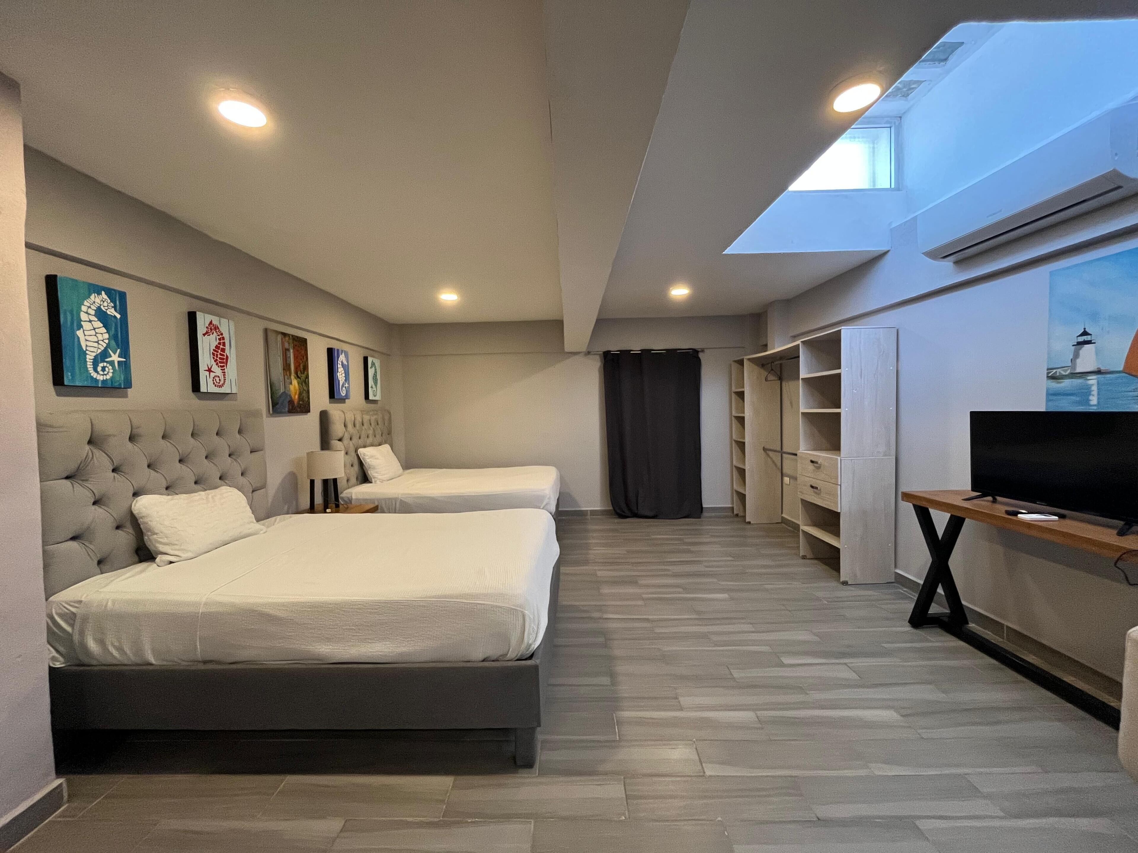 Ein Hotelzimmer mit zwei Betten, einem Fernseher, einem Kleiderschrank und Bildern an den Wänden.