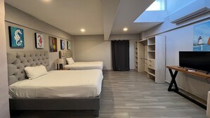A hotel room with two beds, a TV, a wardrobe, and artwork on the walls. - Estudio frente al mar de Cozumel #5 (San Miguel de Cozumel)