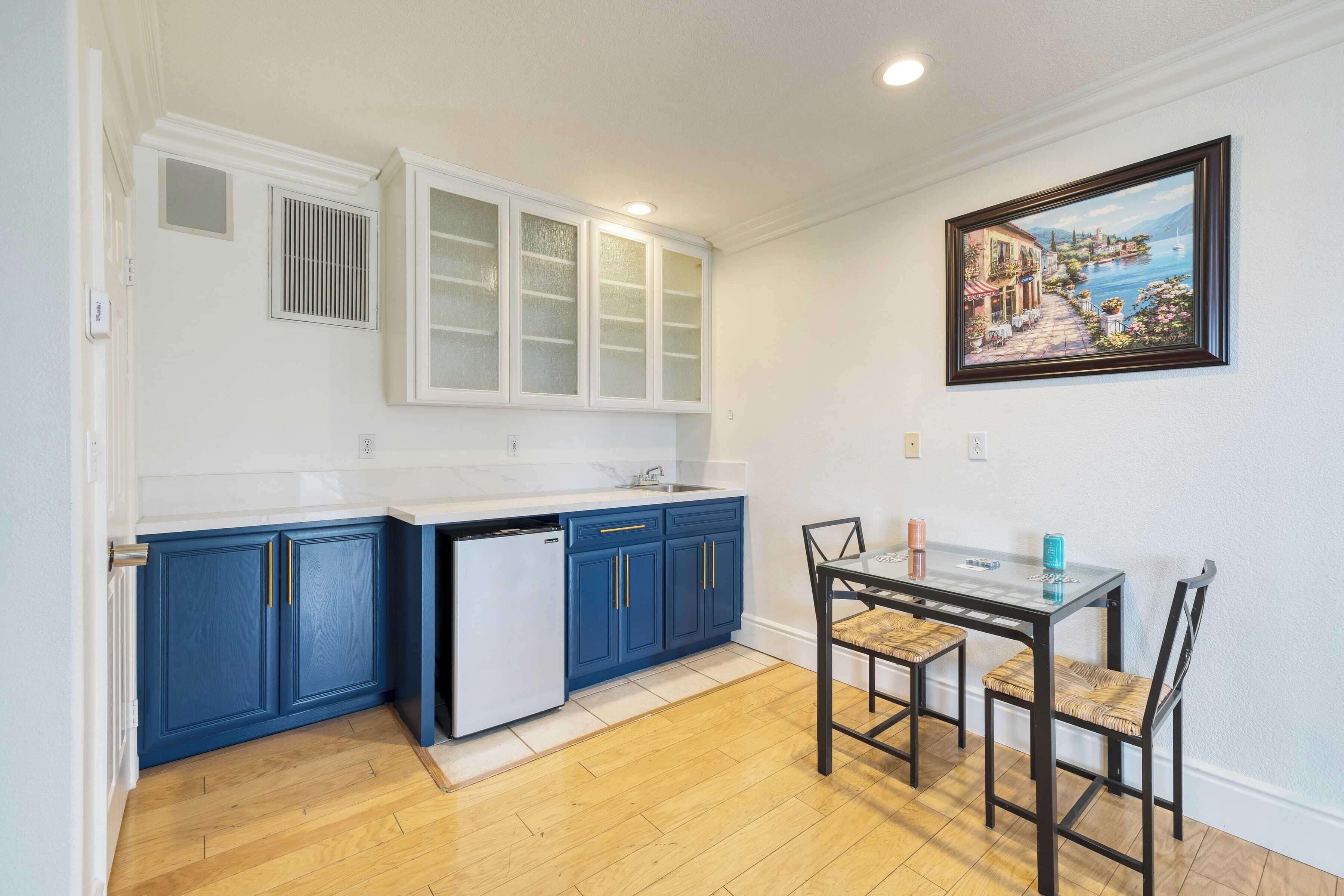 A kitchen with blue cabinets, a white dishwasher, and a dining table with chairs.