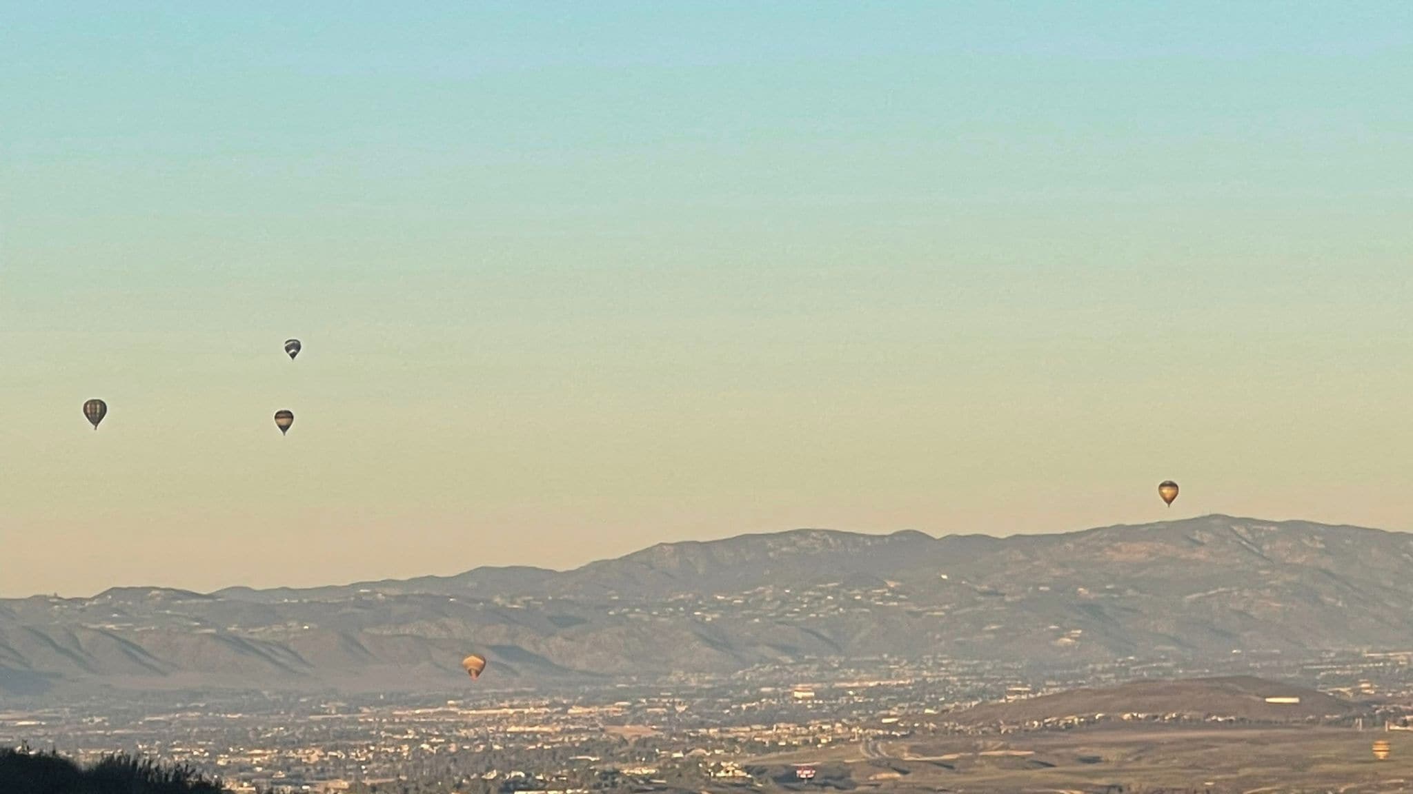 Un paysage de montagnes avec des montgolfières dans le ciel.