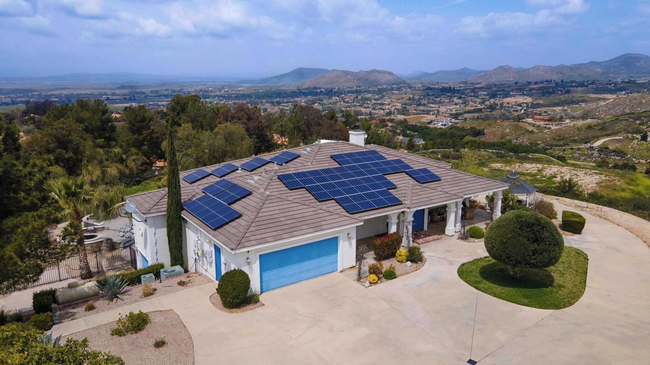 Uma casa com garagem, painéis solares no telhado e um gramado bem cuidado.
