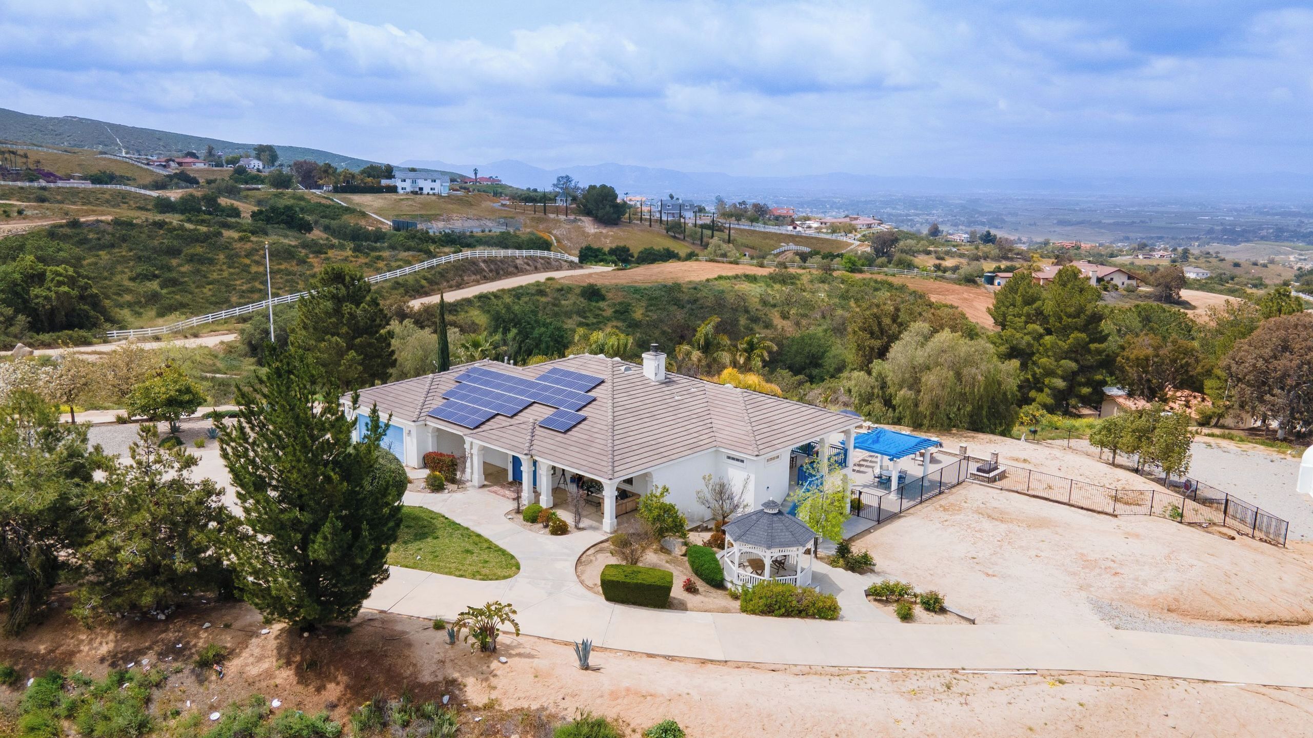 A house with solar panels, a covered patio, and a view of the surrounding landscape.