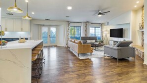 A spacious living area with a kitchen, a sofa, a TV, and a balcony. - 5-acre Hilltop Estate w/ Resort Pool + Game Room Le Grand Bleu by Avantstay (Temecula)