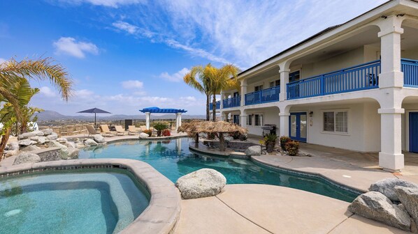 A pool area with a curved pool, lounge chairs, and a building with blue railings. - 5-acre Hilltop Estate w/ Resort Pool + Game Room Le Grand Bleu by Avantstay (Temecula)