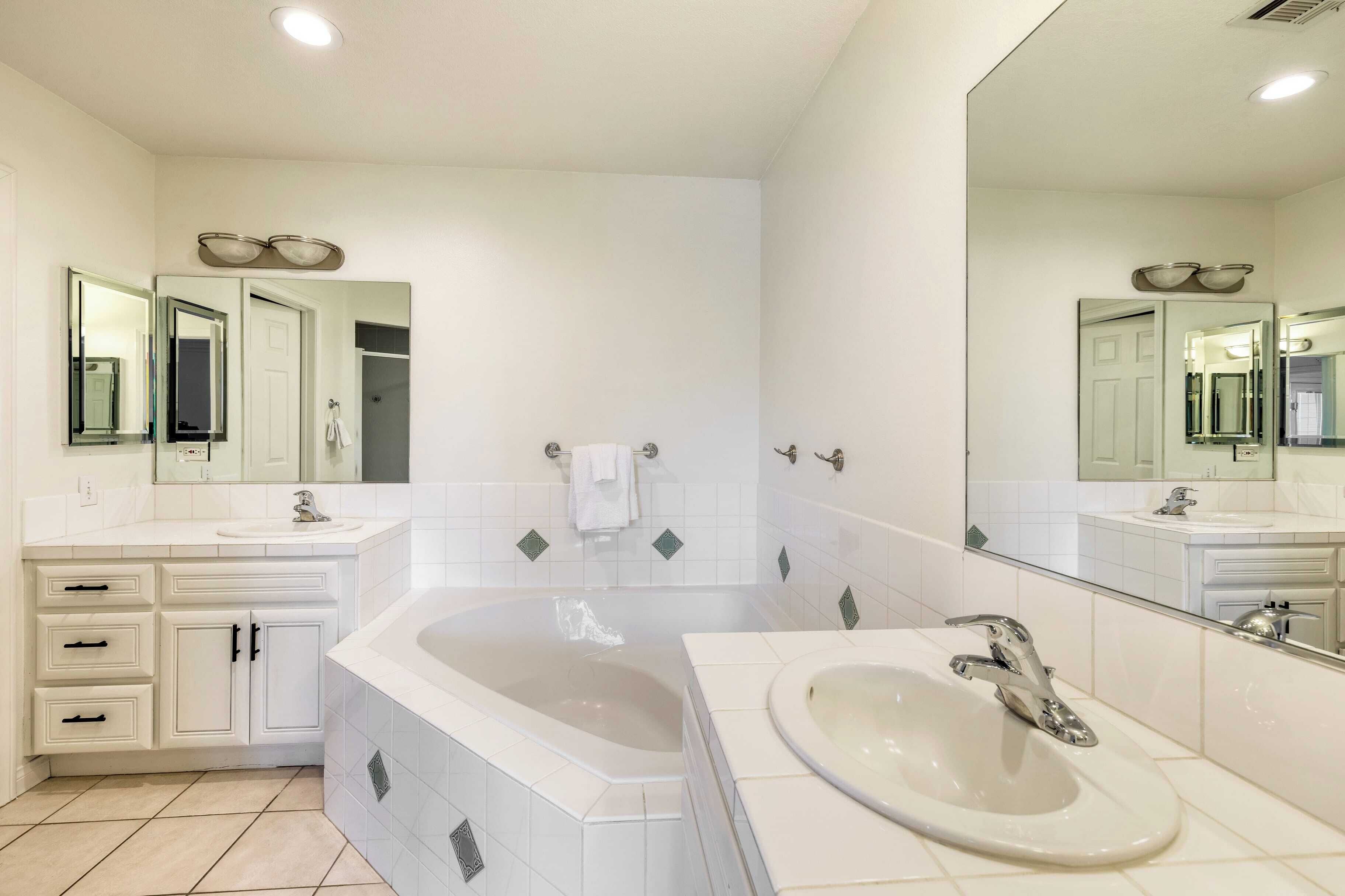 Une salle de bain moderne avec une grande baignoire, deux lavabos et un miroir au-dessus de chaque lavabo.