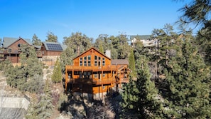 A large wooden cabin with multiple decks, surrounded by dense pine trees. - Starlight Retreat by Avantstay Gorgeous Log Style Home w/ Incredible Views! (Big Bear Lake)