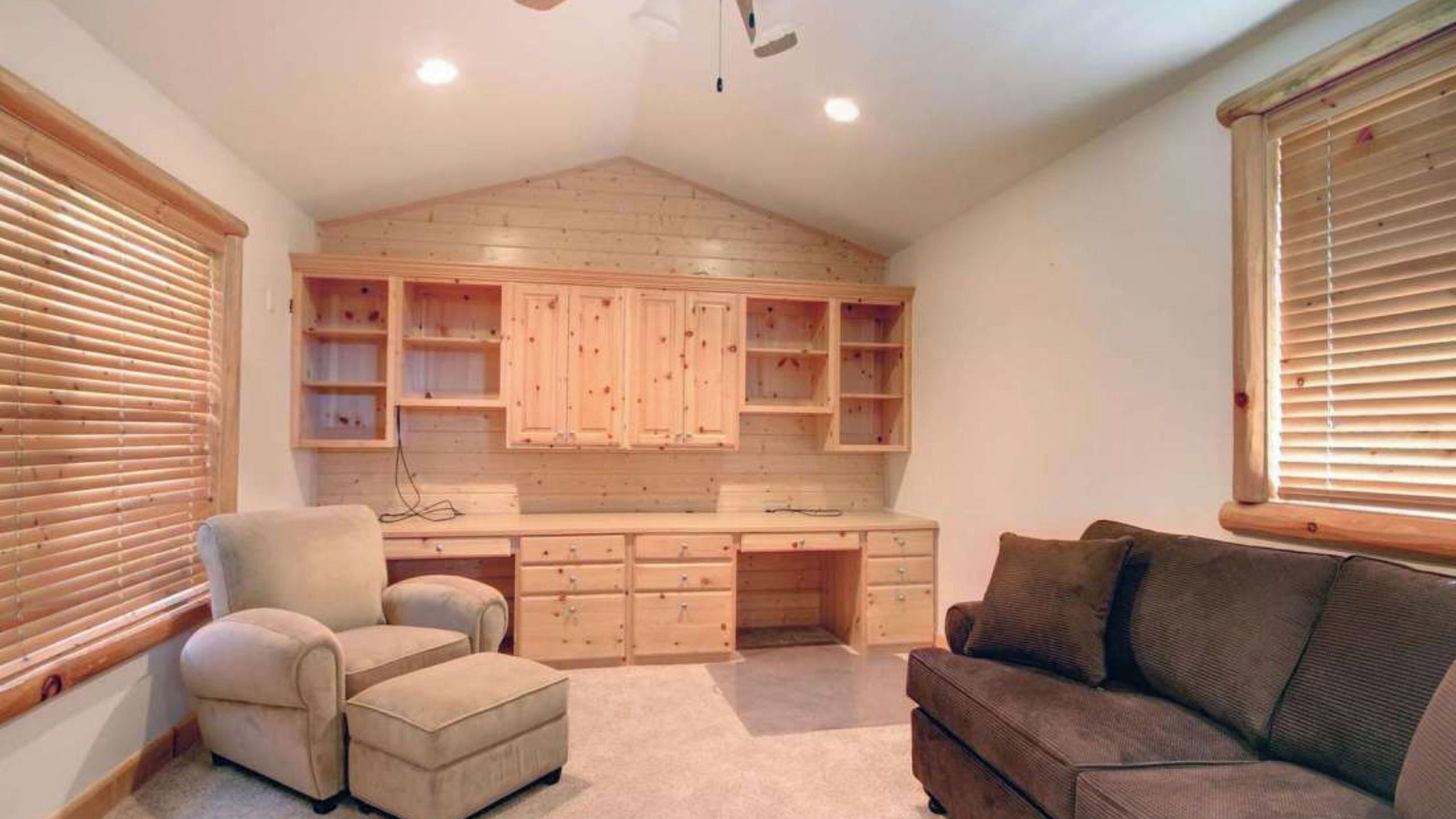 Una habitación con techo de madera, armarios empotrados, un escritorio, una silla y un sofá.