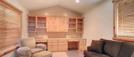 Una habitación con techo de madera, armarios empotrados, un escritorio, una silla y un sofá.