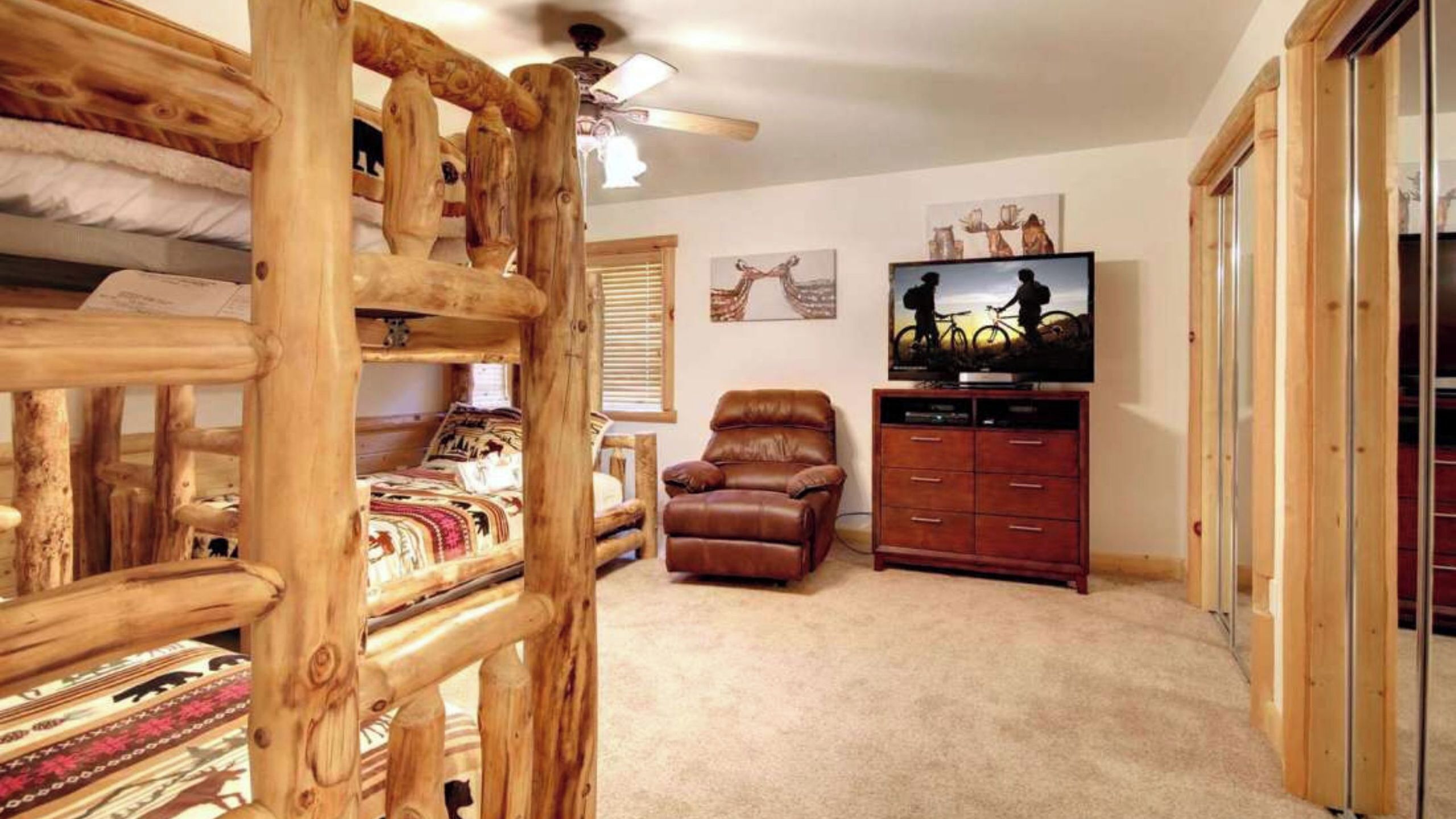 A room with a bunk bed, a leather recliner, a TV, and a wooden wardrobe.